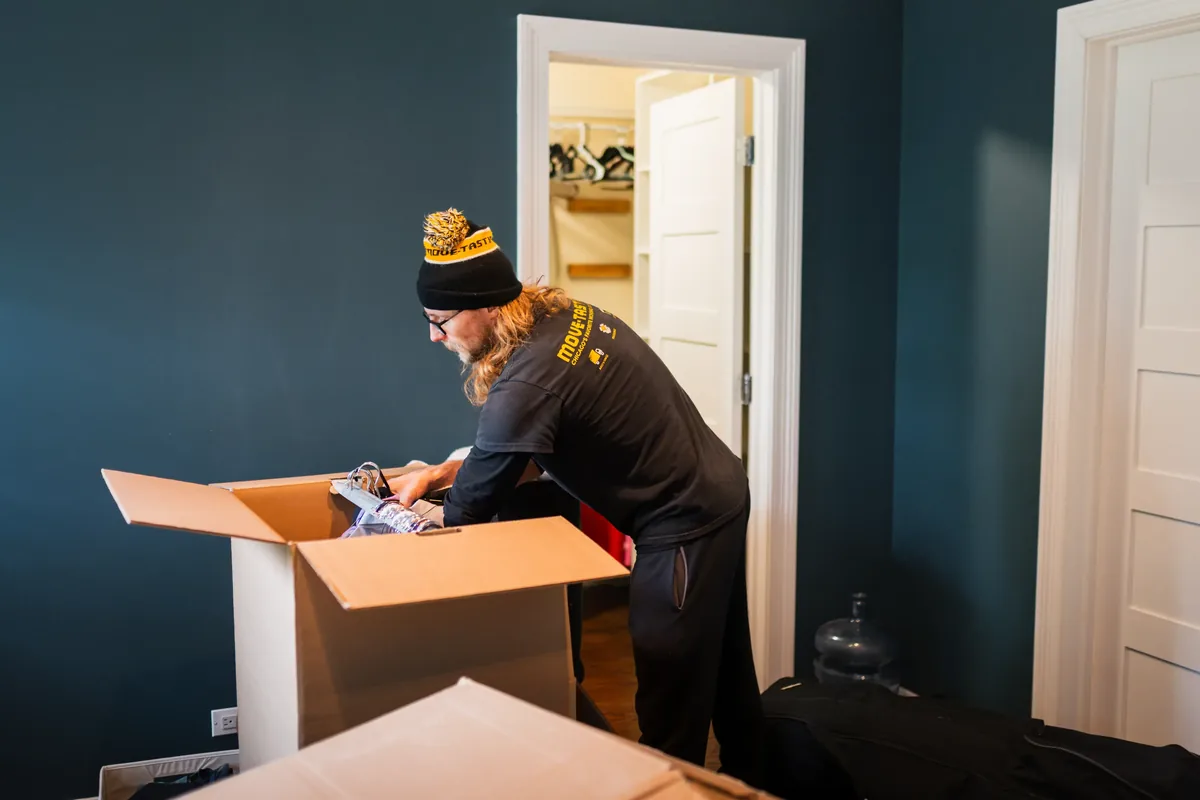 Move-tastic! mover packing a box in a bedroom